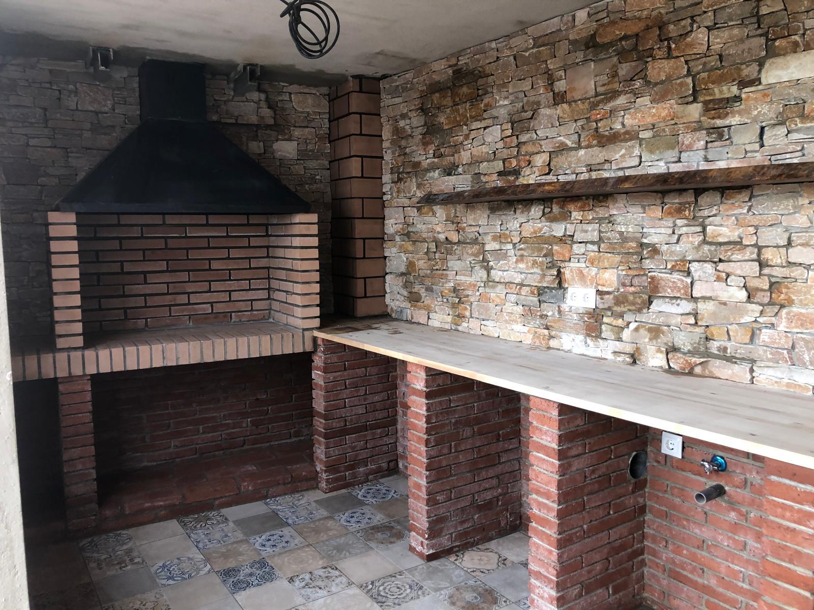 Barbacoa de obra con piedra natural en jardín de Sant Cugat